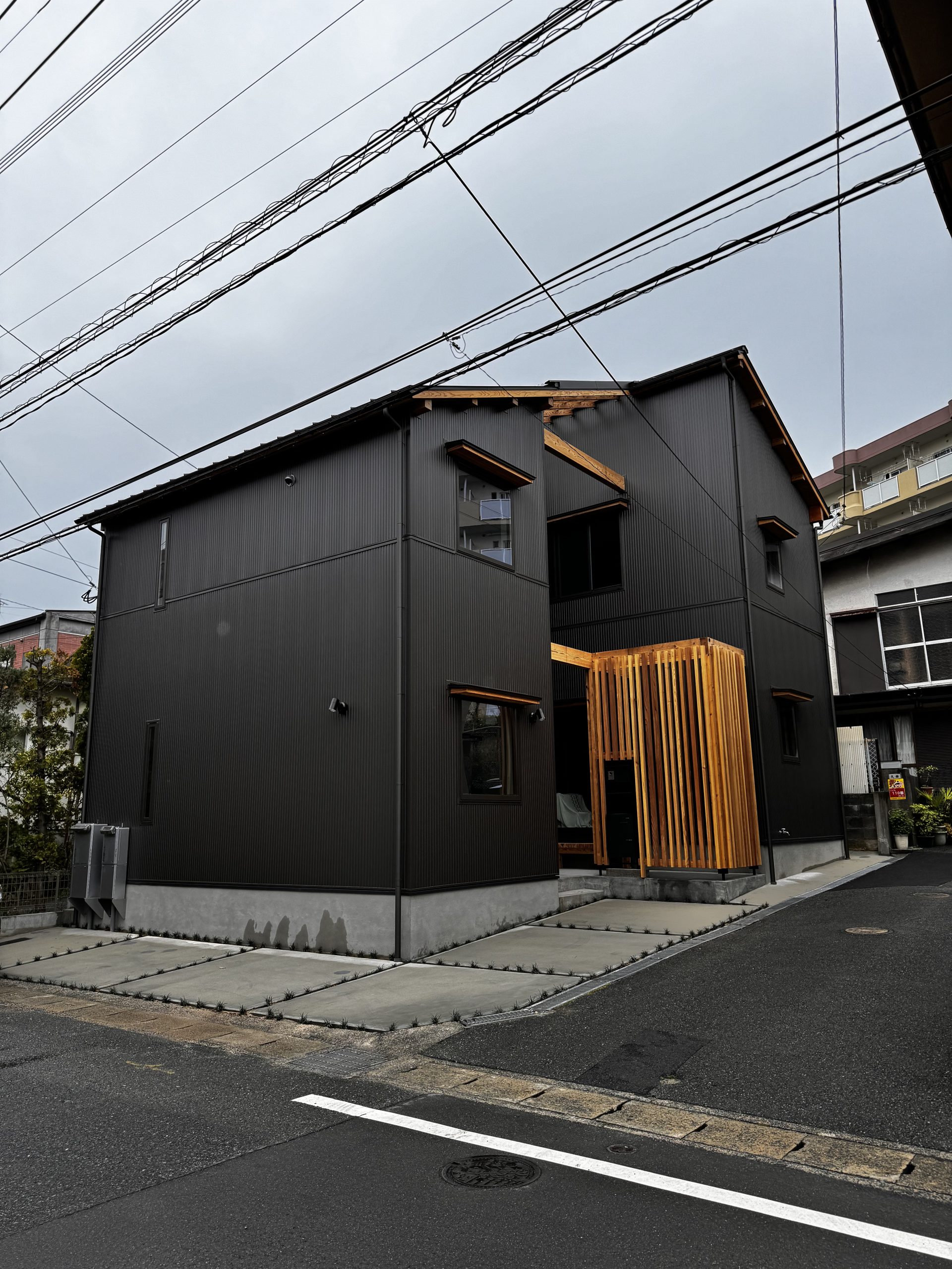 ザイツ建築が手がけた福岡県福岡市南区にある住宅のコの字型の外観、コの字のくぼんだ位置に玄関、外壁はガルバ制サイディング材